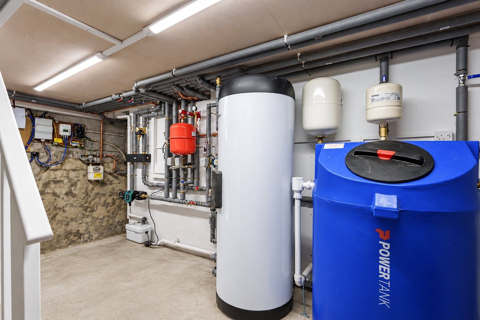 A plant room with an unvented hot water cylinder, expansion vessels and insulated pipework