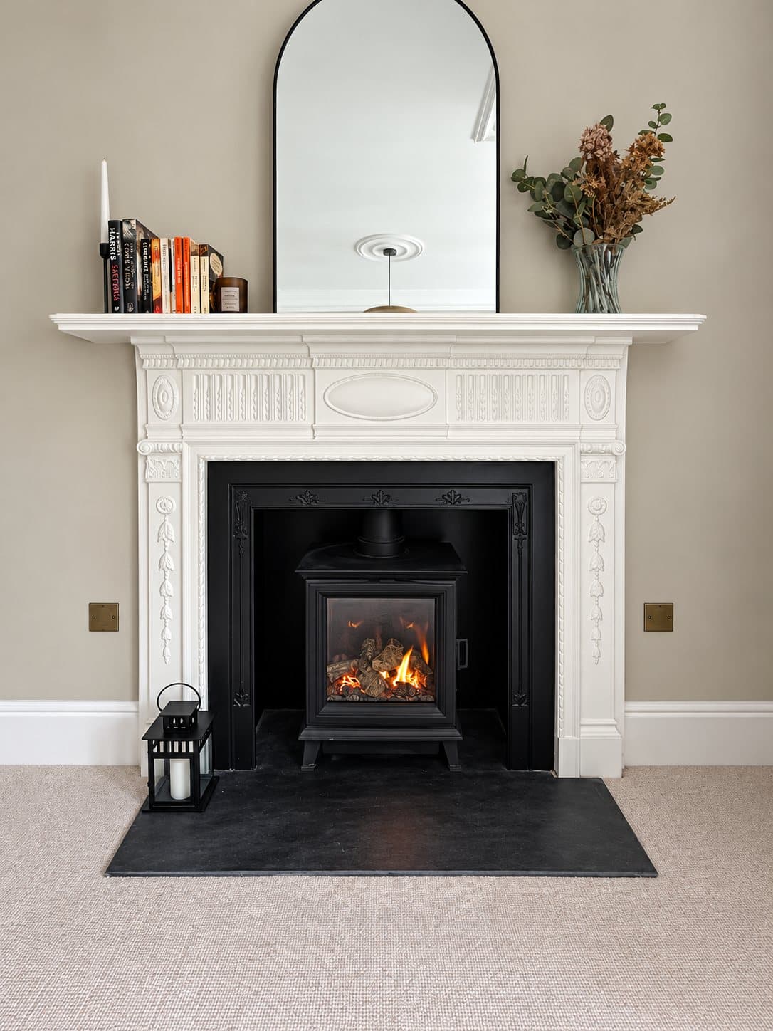 A gas stove in a period fireplace with a white surround