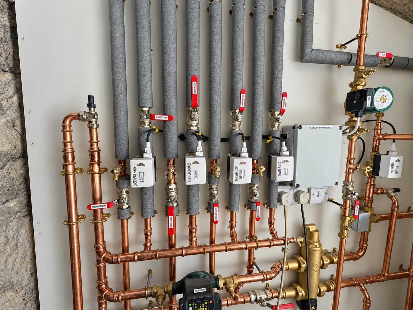 Copper pipework and labelled zone valves for radiators, underfloor heating, towel rails and hot water